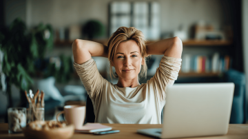 Žena sedí u počítače a radostně se protahuje